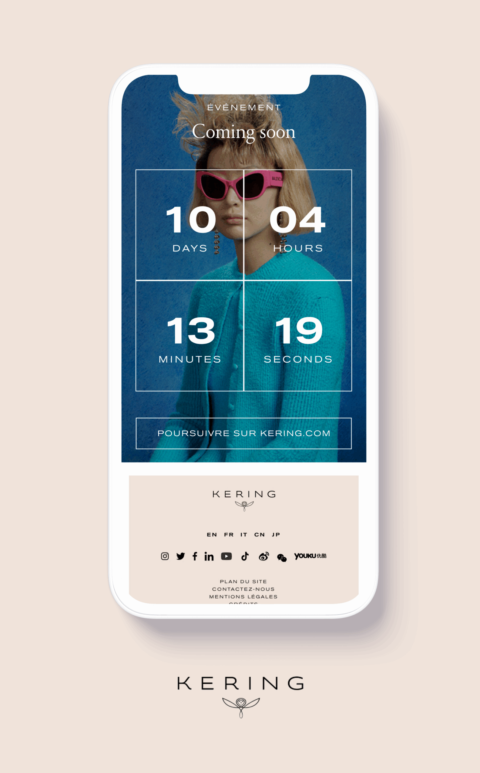 Visuel d’un smartphone affichant une page d’événement Kering, avec en arrière-plan une personne vêtue d’un cardigan bleu turquoise. Un compte à rebours est visible, indiquant le nombre de jours, heures, minutes et secondes avant le début de l’événement (Coming soon). Sous le compte à rebours, un bouton invite à poursuivre sur le site kering.com. Le bas du visuel présente le logo Kering, des liens vers les réseaux sociaux et des options de langue.